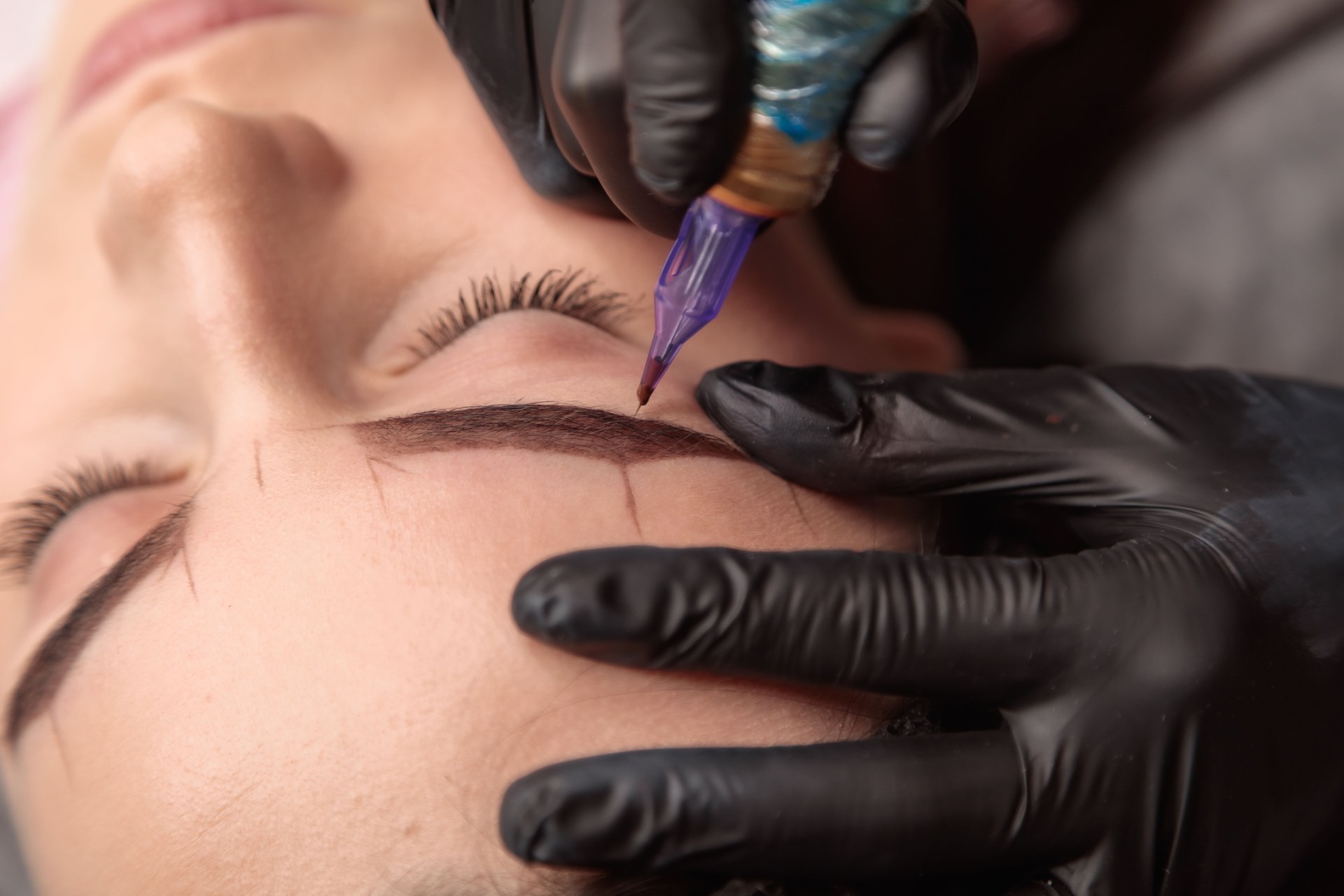 Beautician applying permanent makeup on eyebrows of client